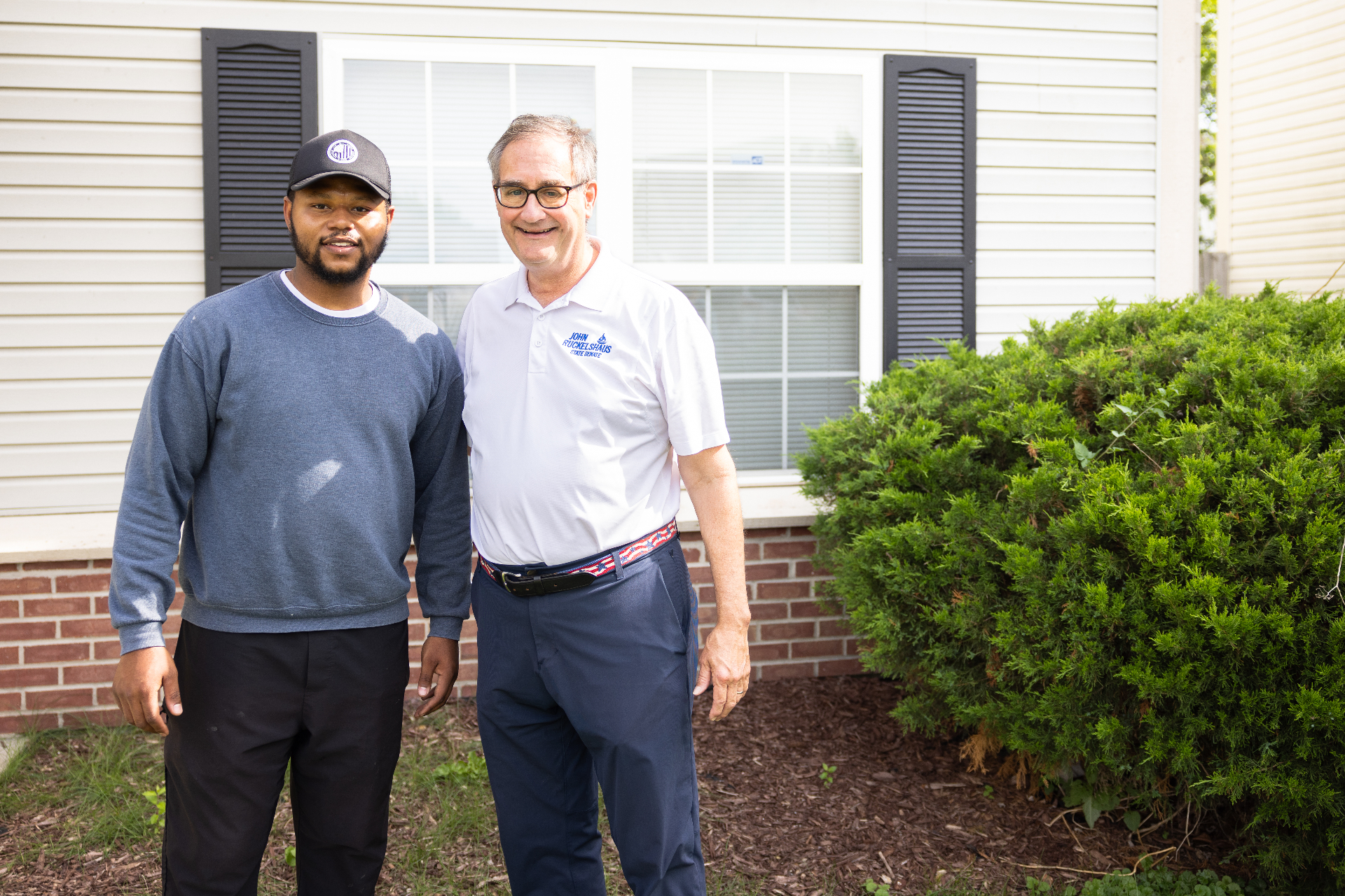 John Ruckelshaus standing with a community supporter in front of a home