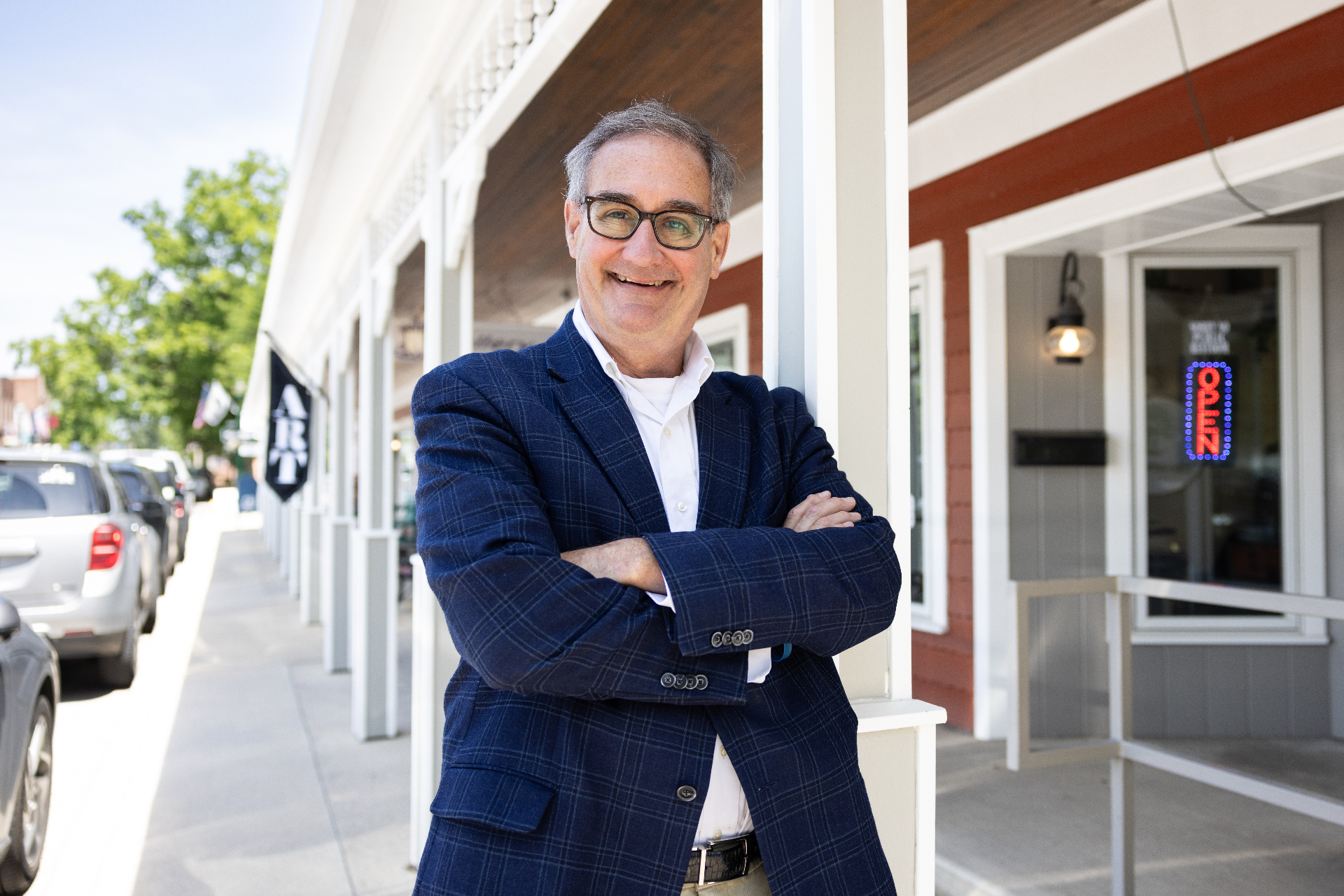 John Ruckelshaus with arms crossed, smiling in a navy plaid jacket